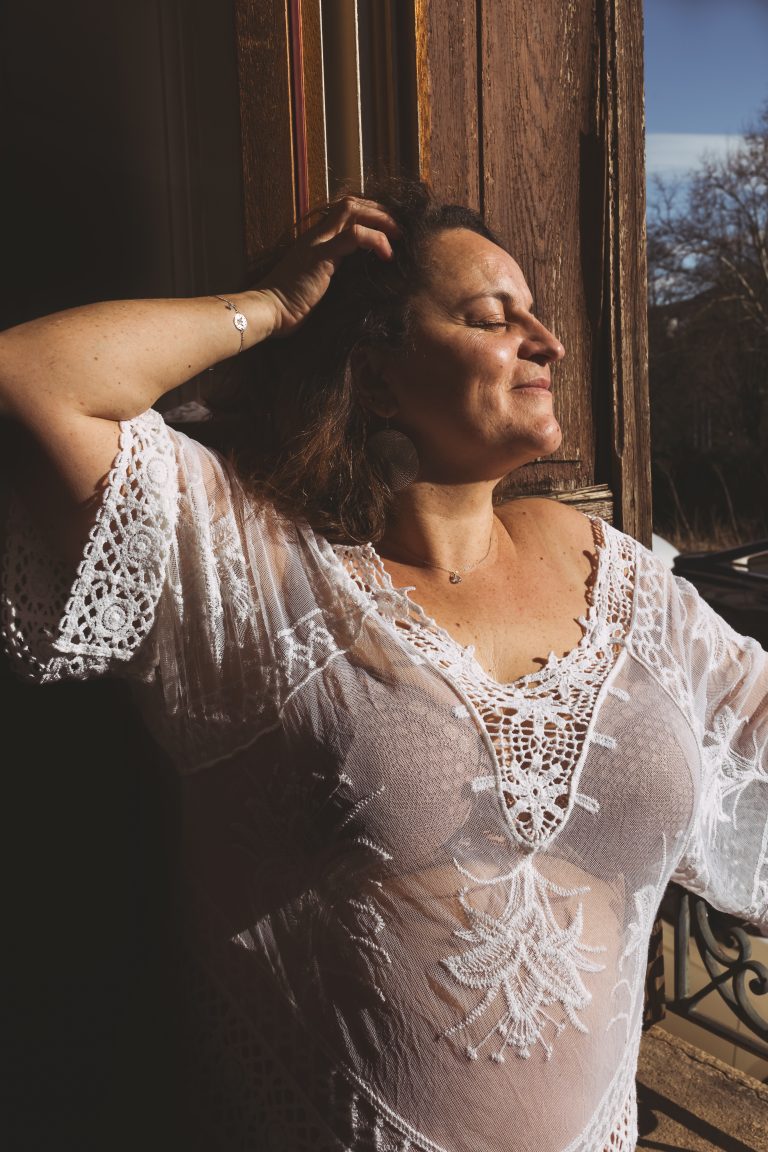photo d'une femme qui sourit en prenant le soleil à sa fenêtre