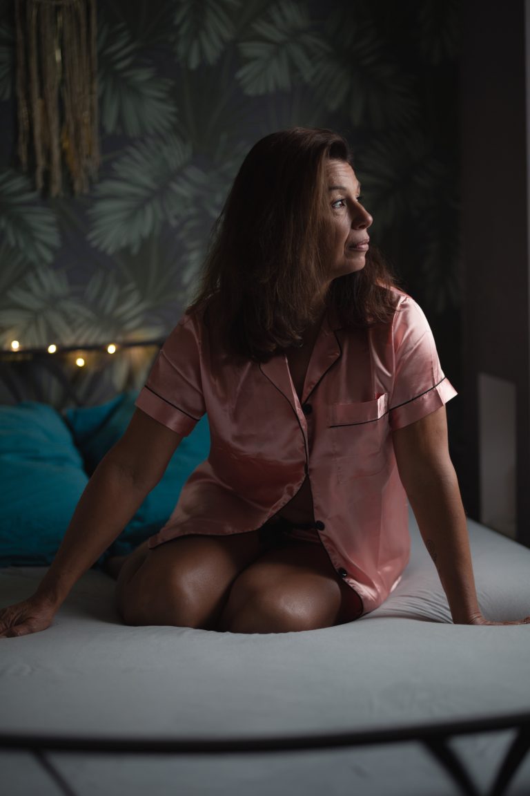 photo intimiste de femme regardant pas la fenêtre avec un pyjama rose en satin